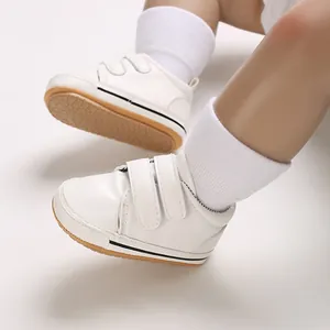 Close-up of white baby walking shoes with dual Velcro straps and anti-slip rubber sole.