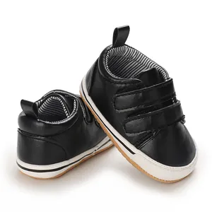 Detailed view of black faux leather baby sneakers with white non-slip soles and velcro
