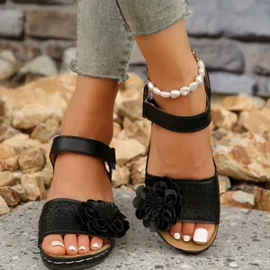 Detaillierte Nahaufnahme schwarzer Damen-Keilsandalen mit elegantem, hohlem Blumendesign