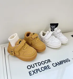 Close-up detail of mustard yellow and white toddler sneakers with velcro straps