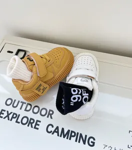 Close-up of yellow and white toddler sneakers with Velcro straps on outdoor background.