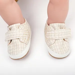 Nahaufnahme von beigen Tweed-Babyschuhen mit weißen weichen Sohlen und Klettverschluss