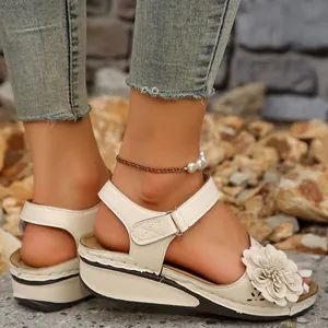 Nahaufnahme weißer Keilsandaletten mit Blumenverzierung und modischem Cut-Out-Design.