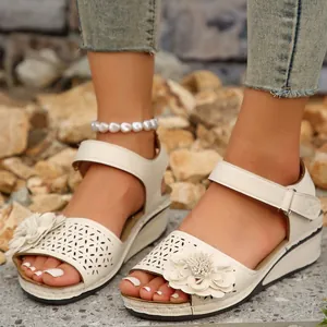 Detailansicht weißer Keilsandalen mit Blumenmuster und Perlenfußkettchen am Fuß