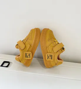 Close-up detail of yellow toddler sneakers featuring non-slip soft soles and Velcro.