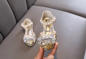 Nahaufnahme goldene Prinzessinnenschuhe mit Kristallblume und Perlenriemen für Mädchen