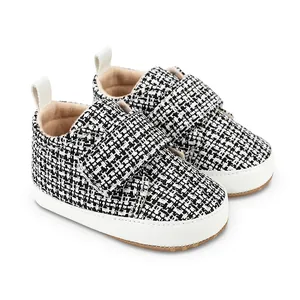 Nahaufnahme der schwarz-weißen Tweed-Babyschuhe mit weichen weißen Sohlen und Klett