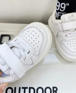 Detailed macro view of white toddler sneakers with adjustable velcro and soft rubber soles