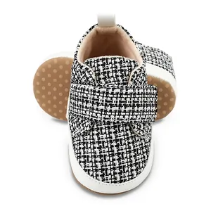 Detailansicht von Baby-Lauflernschuhen mit weicher Sohle und schwarz-weißem Tweed-Muster