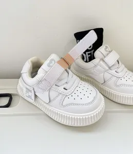 Close-up of white toddler sneakers with adjustable velcro straps and soft rubber soles.