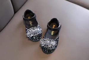 Detailopname van kristallen bloem en strassteentjes op elegante zwarte meisjesschoenen
