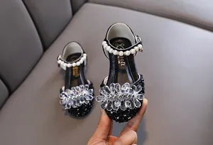 Nahaufnahme der schwarzen Prinzessinnenschuhe für Mädchen mit Kristallblume und Perle