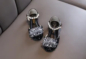 Detail von schwarzen Mädchen Prinzessin Schuhen mit Perlenriemen und Kristallblumen