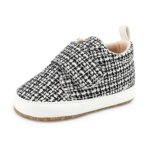 Detailansicht der schwarz-weißen Tweed-Babyschuhe mit weicher weißer Sohle und Klettverschluss
