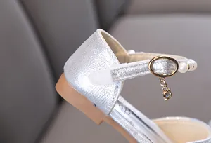 Detailaufnahme silberner Mädchen-Prinzessinnenschuh mit Perlenriemen und Strass-Anhänger