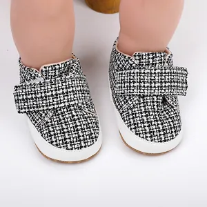 Nahaufnahme von schwarz-weißen Tweed-Lauflernschuhen für Babys mit Klettverschlussriemen