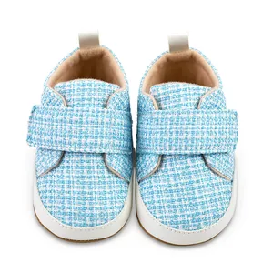 Detailansicht hellblauer Tweed-Babyschuhe mit weichen weißen Sohlen und Klettverschluss.
