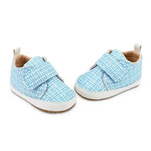 Detail von hellblau karierten Baby-Lernlaufschuhen mit weicher Sohle und Klettverschluss.