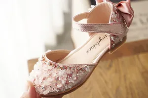 Close-up of pink rhinestone girls' dress shoes with satin bow decoration