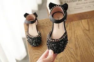 Close-up of sparkling black rhinestone sandals for girls with bow detail