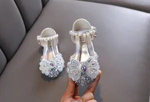 Gros plan de chaussures de princesse argentées avec nœud en strass et perles pour filles.
