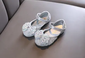 Detalle de zapatos de princesa plateados brillantes para niña con lazo de diamantes
