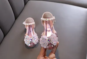 Détail d'une chaussure de princesse rose pour fille avec nœud en strass et perles.