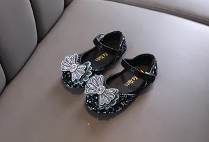 Elegantes zapatos de princesa negros para niñas con un lazo decorativo grande.
