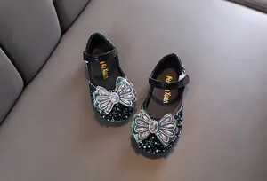 Detalle de zapatos Mary Jane negros brillantes para niña con gran lazo de diamantes