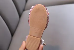 Vue macro de la semelle antidérapante et des paillettes sur une sandale rose pour fille