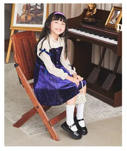 Elegant girls' black patent leather shoes styled with a classic purple velvet dress.