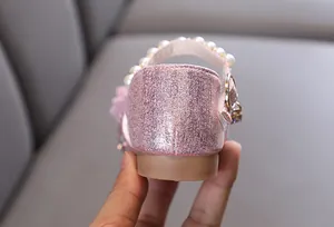 Gros plan de chaussures de fête roses pailletées pour filles avec bride de perles chic