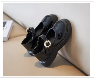 Detail view of glossy black patent leather girls Mary Jane shoes featuring pearl buckle