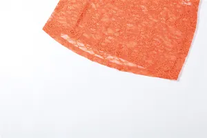 Detailed close-up view of vibrant orange lace fabric with intricate floral patterns