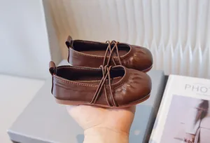 Detalle de bailarinas de cuero marrón suave para niña con un elegante diseño de tiras cruzadas