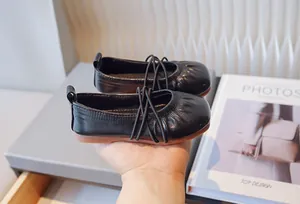 Primer plano detallado de bailarinas vintage de cuero negro para niñas con correas elásticas