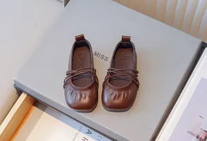 Detalle de preciosas manoletinas retro de piel suave marrón para niñas con tiras cruzadas