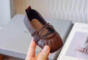 Detalle del suave cuero marrón y las correas cruzadas de las bailarinas de niña
