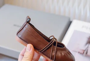 Primer plano de las elegantes bailarinas de cuero marrón para niñas con correas