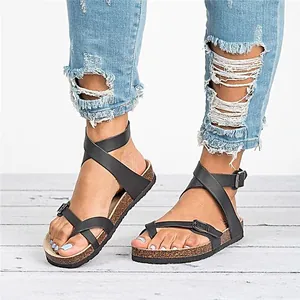 Primer plano de sandalias romanas negras para mujer con hebilla y diseño de dedo