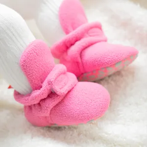 Primer plano de patucos de forro polar rosa suave para bebé con correas de velcro