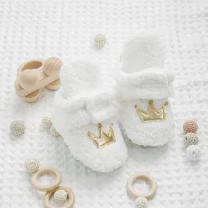 Primer plano de zapatos de bebé blancos afelpados con corona dorada en punto de gofre