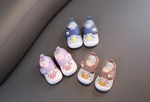 Set of three colorful cartoon squeaky baby walking shoes for toddlers on a gray mat