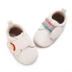 Gedetailleerd overzicht van witte baby-wandelschoenen met kleurrijke regenboog klittenbandsluiting