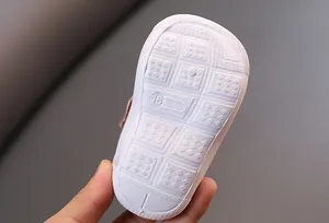 Detailed view of the non-slip white rubber sole of an infant squeaky walking shoe