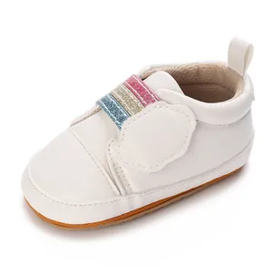 Detail van witte babysneaker met zachte zool en regenboog glitter elastiek.