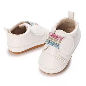Detailweergave van witte babyschoenen met regenboog klittenband en zachte zool