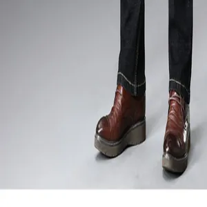 Detail of men's dark blue straight-leg denim jeans hem paired with brown leather shoes.