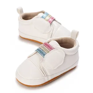 Close-up van witte babysneakers met zachte zolen en kleurrijke glitterbandjes