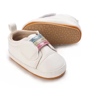 Detailopname van witte baby-sneakers met zachte zool en glitter regenboog bandjes